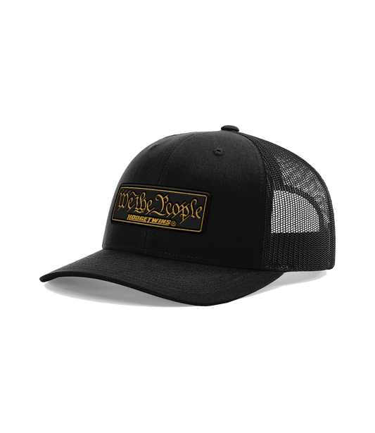 Black OSFA mesh hat with a black and gold leather patch that reads We The People