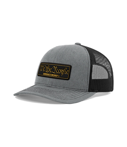 Grey front black mesh OSFA mesh hat with a black and gold leather patch that reads We The People